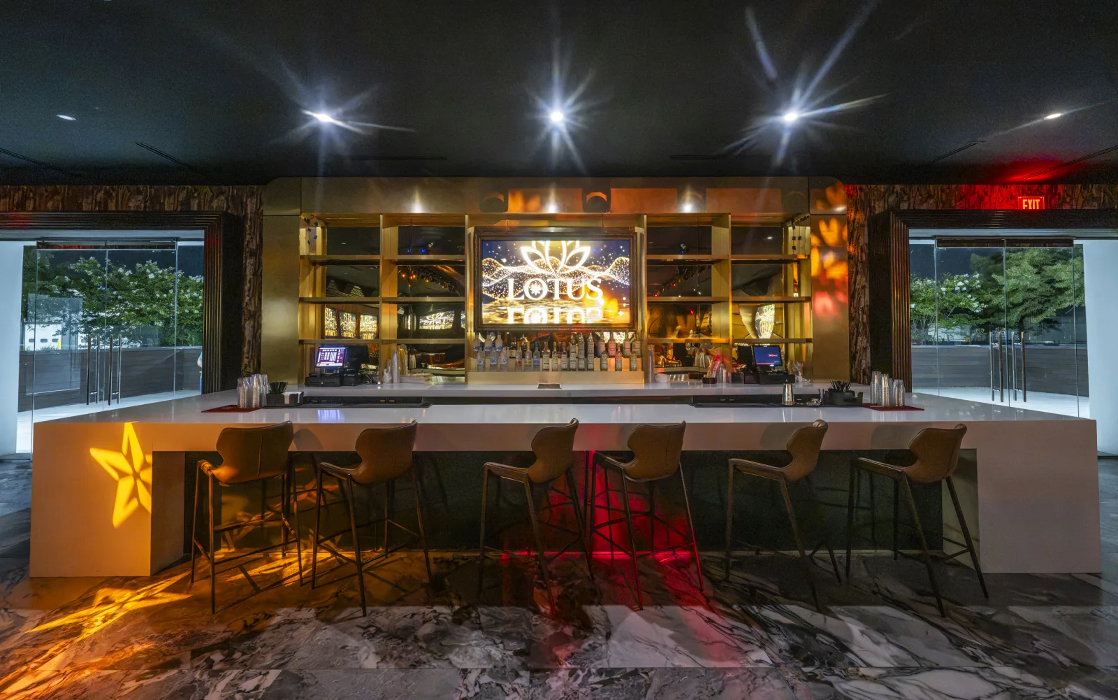The front bar at Lotus, lit gold, with floor-to-ceiling windows.