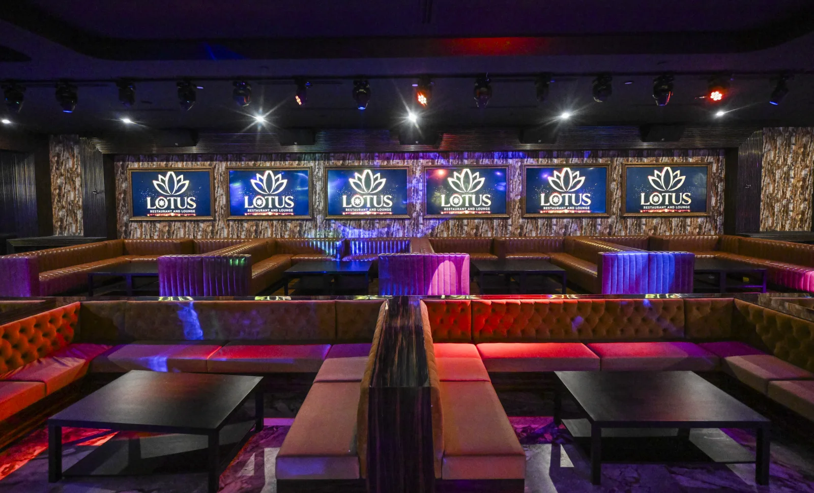 Tufted leather booths facing a wall of backlit LOTUS screens.