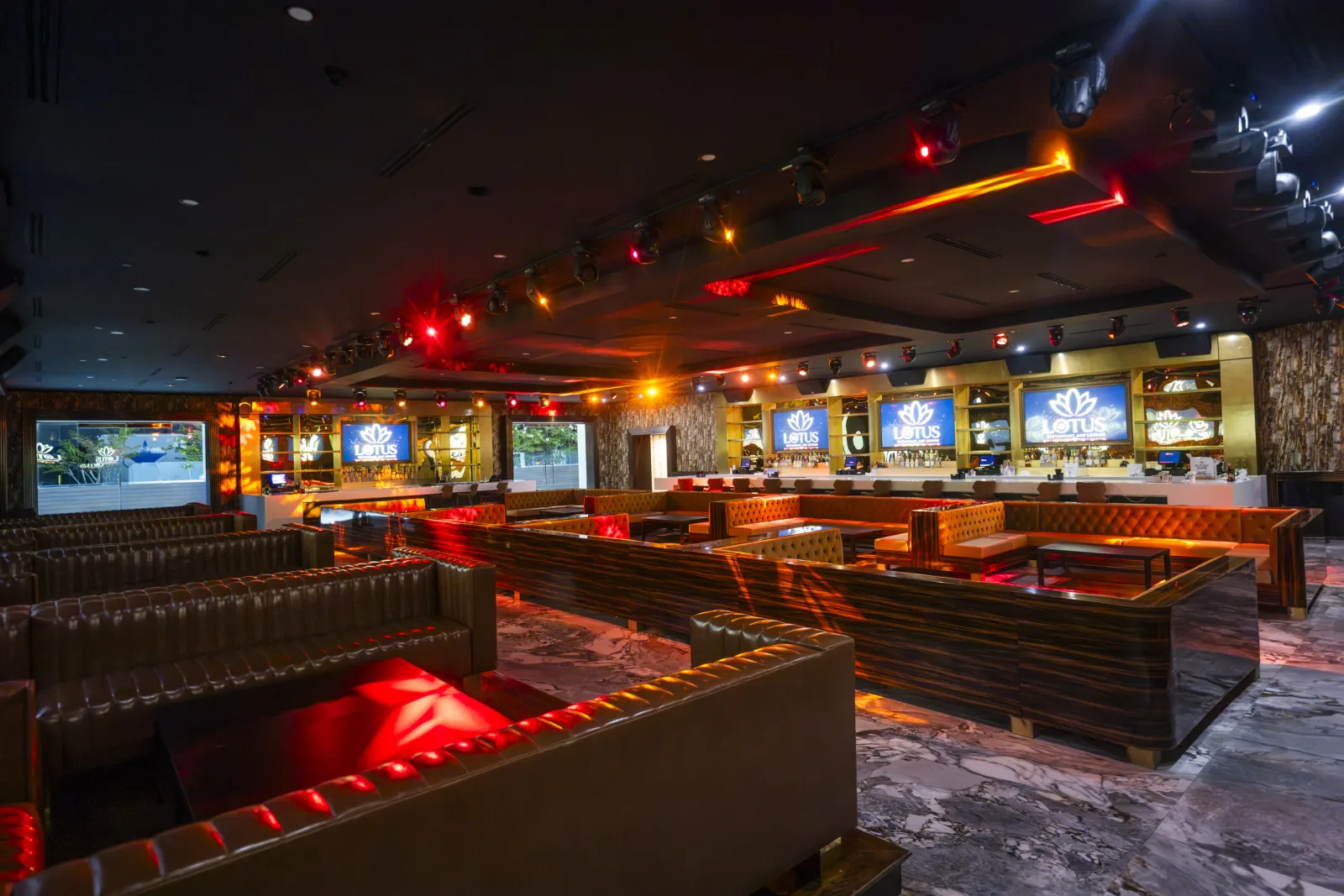 The lounge in red light — leather booths and the long marble bar.