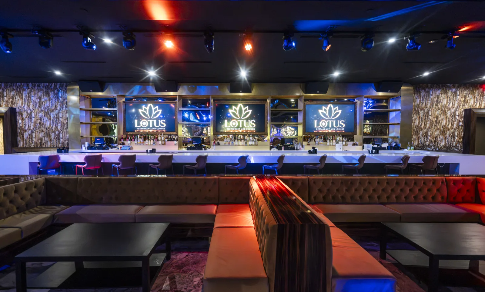 The bar at Lotus in blue and amber light, LOTUS crests behind the bottles.